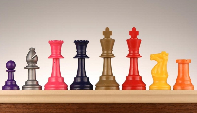 colorful line up of chess pieces (pink, yellow, purple, brown, and black)